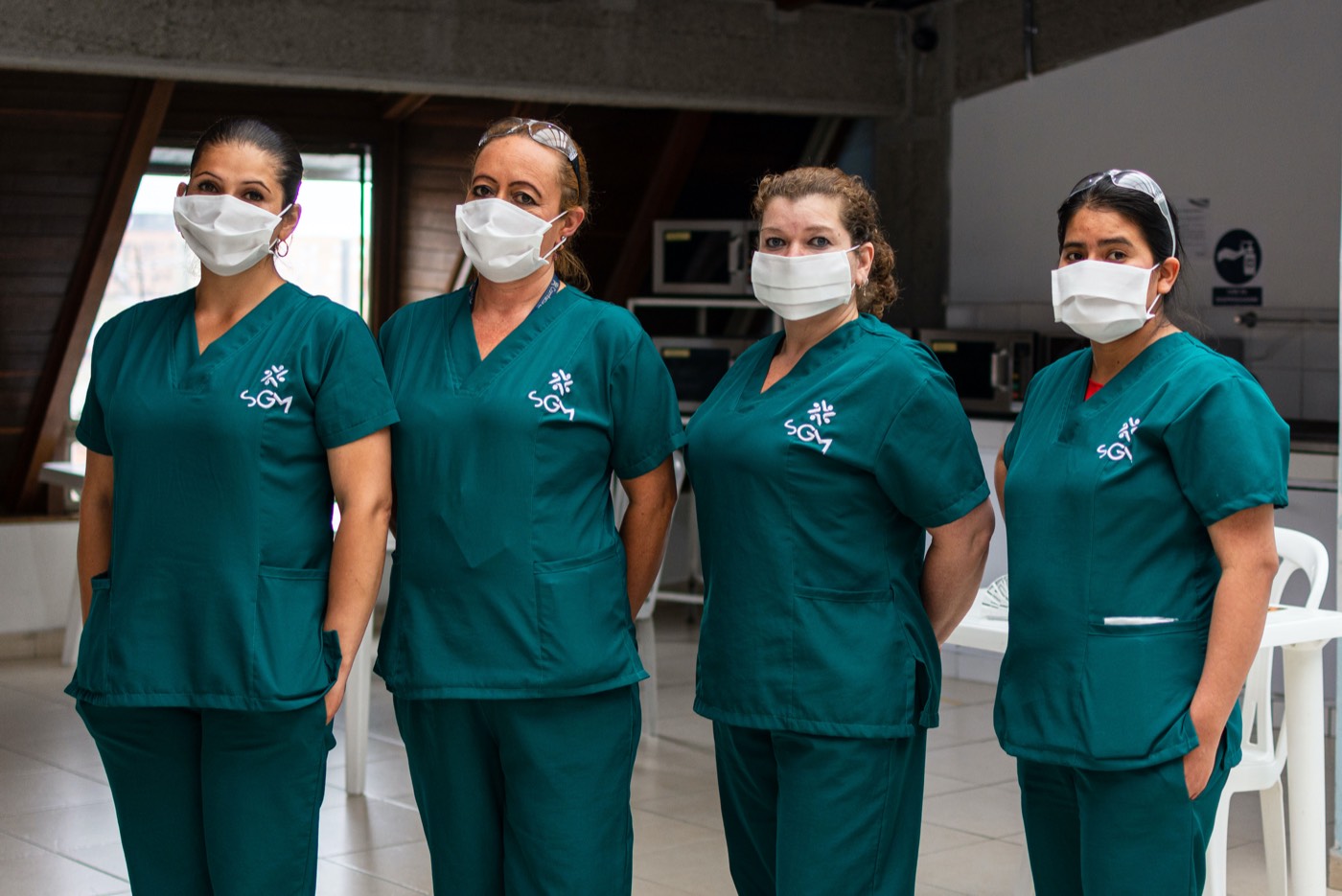 Cuatro integrantes del equipo de Tkuido con uniforme verde y tapabocas en una sede cliente